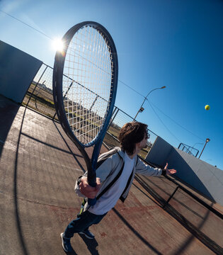 Young Player Prepares to Hit a Tennis Ball Under Bright Sunlight
