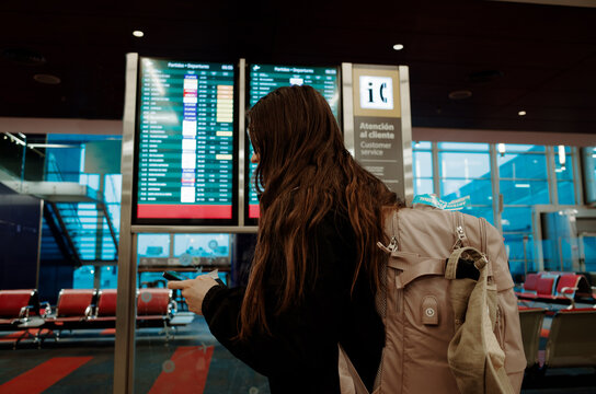Woman Checking Flight Information at Airport Departure Terminal