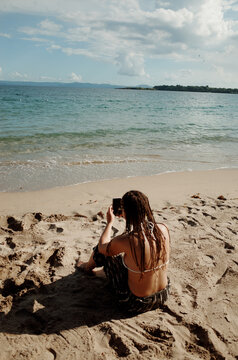Person Taking Photos on the Beach With Calm Waves and Sunny Skies