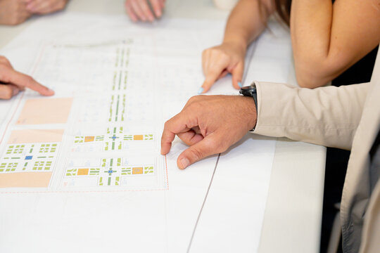 Hands pointing at architectural plans on table