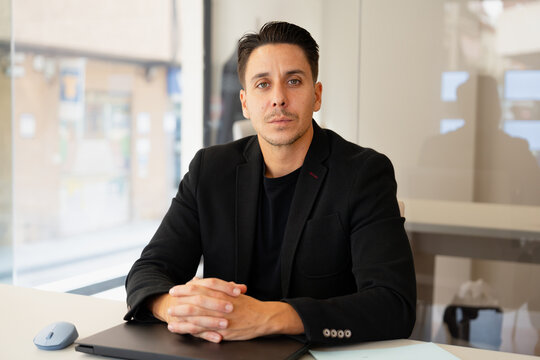 Confident man sitting at desk in modern office