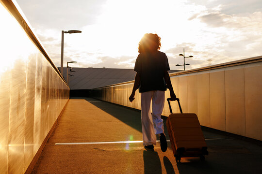 Traveler with suitcase walking at sunset