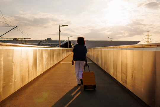 Traveler with suitcase walking at sunset