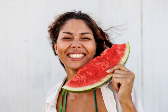 Young woman smiling while holding a large slice of fresh watermelon
