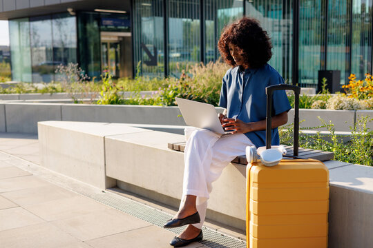 Stylish Female Traveler Remote Work Setup with Yellow Suitcase