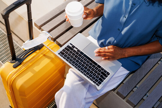 Woman Typing on Laptop Outdoors with Suitcase