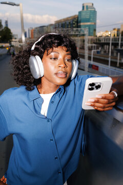 Woman Listening to Music on Headphones on City Train Platform
