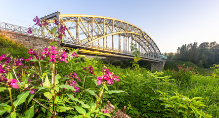 View on the steel arch bridge across the Msta river in summer in sunset light. Built in 1905. Borovichi, Russia