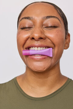 Beautiful mixed race woman holding lipgloss in teeth