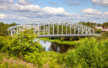View on the steel arch bridge across the Msta river in summer. Built in 1905. Borovichi, Russia
