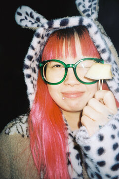 Asian woman with pink hair and a rabbit hoodie eating 