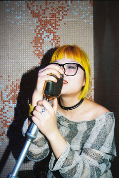 Young blonde asian woman singing karaoke