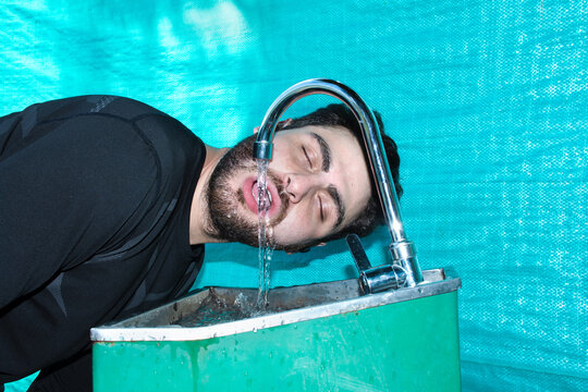 Man Enjoys Refreshing Drink From Water Fountain on a Sunny Day