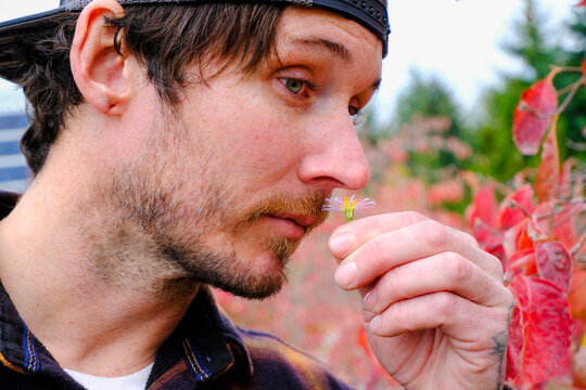 man smelling flowers at park 