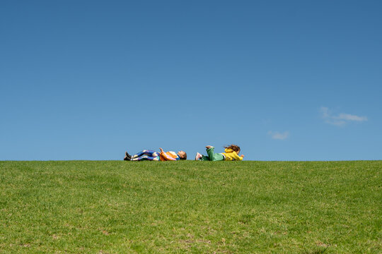 Kids playing roly poly on grassy hill