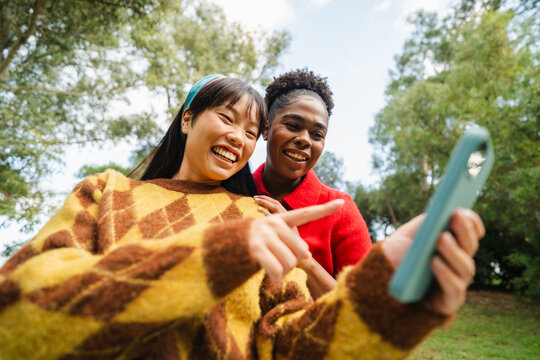 Women excitedly take selfies in the park