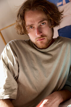 Portrait of man sitting on bed in soft sunlight