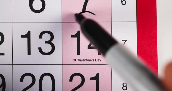 Footage of a calendar showing the date February 14th which is St. Valentine's Day romantic day reminder concept for Feb 14th with a black pen circling the date as a reminder of the day