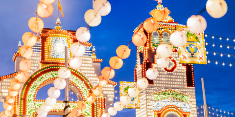 Night view of colorful paper lanterns and illuminated fairground entrance at dusk