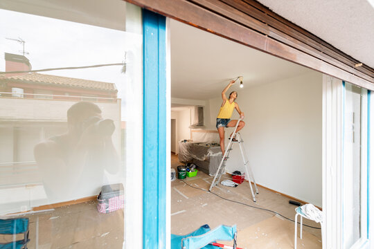 Woman painting ceiling during home renovation