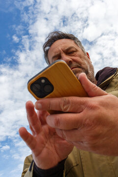 Man Using Smartphone Under a Blue Cloudy Sky