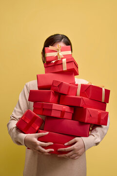 Woman holding a stack of red gift boxes with gold ribbons