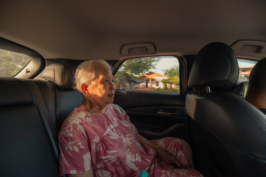 Asian senior woman sitting in a car during sunset drive