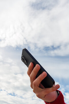 Person Holding Smartphone Against a Cloudy Sky