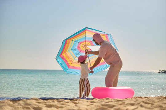Father and Son Setting Up Beach Umbrella Together
