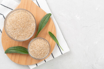 Psyllium husk powder with fresh leaves on concrete background, top view
