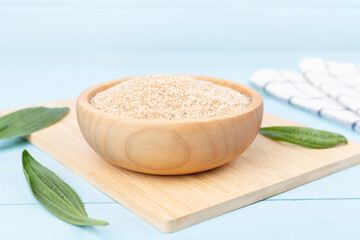 Psyllium husk powder with fresh leaves on wooden table