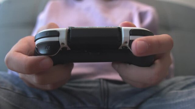 Boy playing video game while sitting on the couch, challenging and achieving eSports goals in the living room. video game.