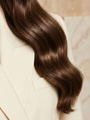 Naklejka premium Long brown hair styled in waves against a light background