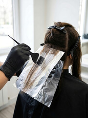 Naklejka premium Client gets hair treatment with foil and brush in salon during the day