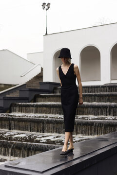 The girl standing on a ledge beside a serene cascade.
