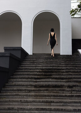 The girl walking up the stairs moving to the white archs.
