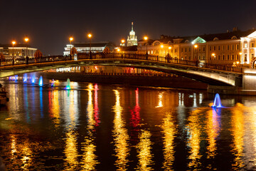 Fototapeta premium Bright lights reflect on the water in Moscow at night near a bridge