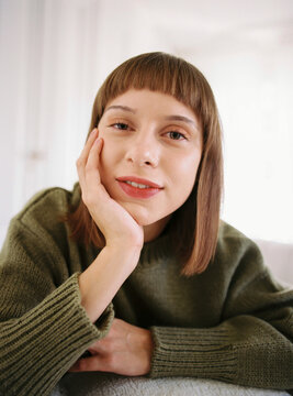 Smiling woman looking at camera while resting on white sofa