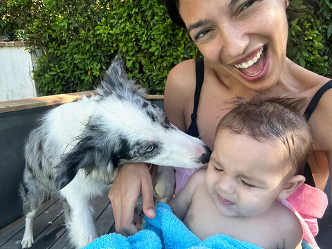 Selfie of a Smiling Woman Holding Baby and dog