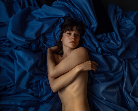 A girl laying on a bed looking to the camera