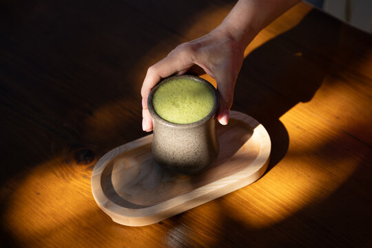 Drinking matcha latte drink on sunlit table 