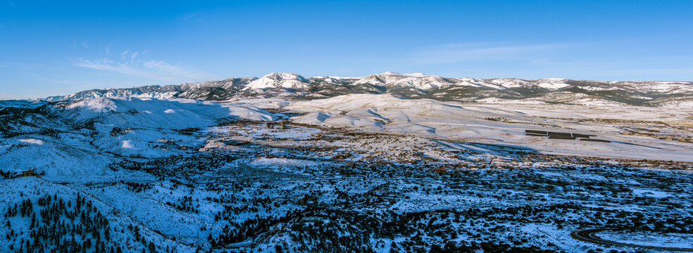 Aerial view of Mt. Rose, Nevada, USA, showcasing a snow-covered mountainous landscape. The peaks, part of the Sierra Nevada range, are accentuated by a clear blue sky. 