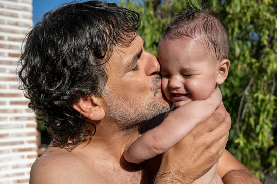 Man Kissing Baby Outdoors In Summer Sun