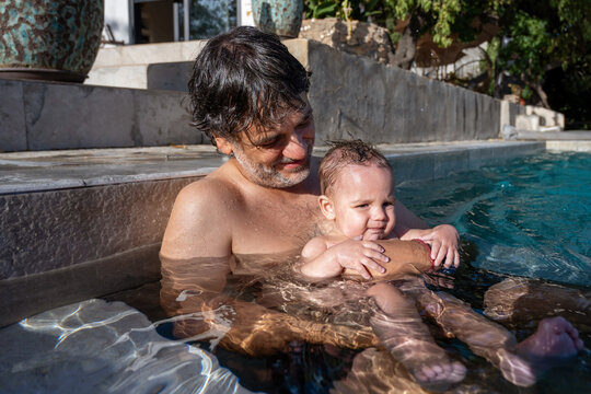 Man Holding Baby In Swimming Pool