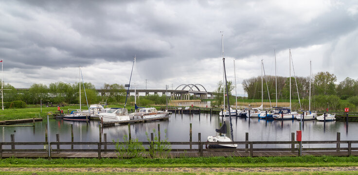 Stormy sky above a quiet marina with sailboats and reflections on the shore. In the background, a highway bridge over the St&ouml;r River. Itzehoe. Germany.