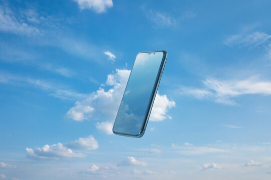 Floating smartphone reflecting sky and clouds