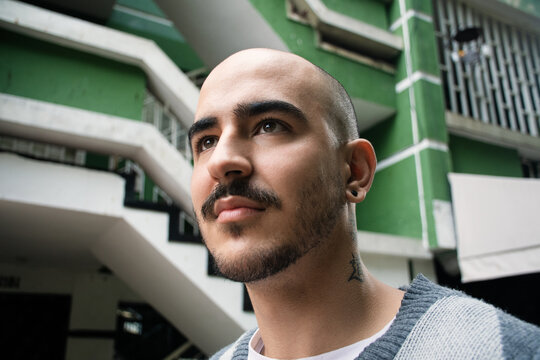 Man With a Shaved Head Poses in a Modern Urban Setting