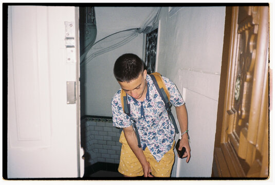 Young Man Heads Downstairs in a Colorful Outfit at a Building Entrance