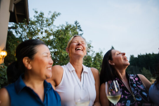 Candid moment of friends laughing and enjoying wine outdoors