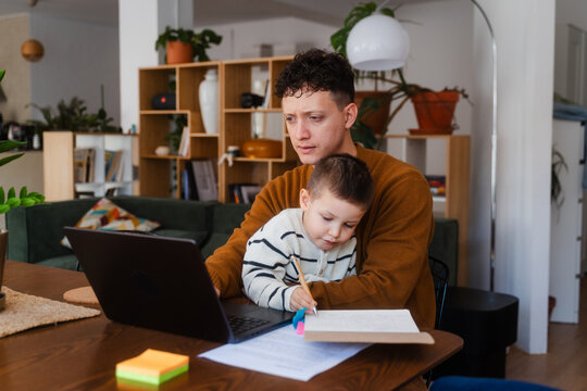 Man babysitting his son while working remotely